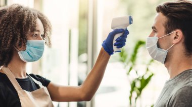 Salgından sonra normal. Kadın berber. Muayene öncesi vücut ısısını inceliyor.