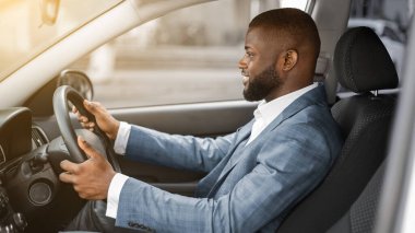 Üretken bir iş gününden sonra eve dönen yakışıklı zenci işadamı. Neşeli Afro-Amerikan sakallı, şık takım elbiseli genç adam araba sürüyor, güneş parlıyor, fotokopi çekiyor.