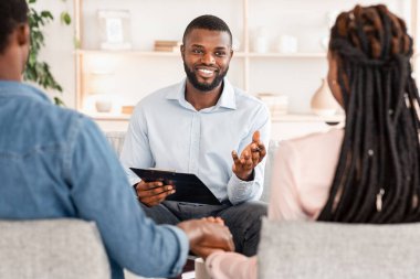 Çiftler için psikolojik yardım. Terapi sırasında eşleriyle konuşan dost canlısı siyah aile danışmanı.