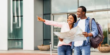 Birlikte seyahat ediyoruz. Yeni Ülke 'ye vardıktan sonra şehir haritası yakınında duran mutlu siyah çift, neşeli Afrikalı eşler seyahat güzergahı planlıyorlar,