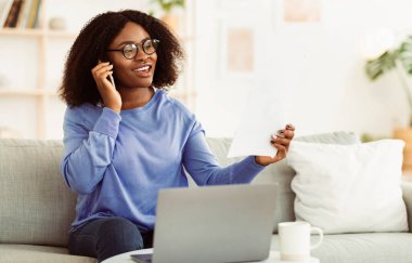 İçişleri Bakanlığı. Genç siyahi iş kadını gazetelerle çalışıyor ve evde müşteriyle telefonda konuşuyor mali belgeleri ve raporları kontrol ediyor. Afrika kökenli Amerikalı İşçi Yönetici Girişimi, Boşluğu Kopyala