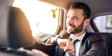 Neşeli iş adamı saatine bakıyor. Arabayla buluşmaya gidiyor. Tam zamanında.