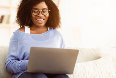 Evindeki yatağında dizüstü bilgisayarı üzerinde çalışan sıradan, güzel afro kadın.