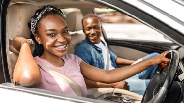 Neşeli Afro-Amerikan milenyum çifti birlikte araba gezisi yapıyorlar, yaz tatilinin tadını çıkarıyorlar, güzel siyahi bayan sürücü ve yakışıklı erkek arkadaşı yeni araba ve uzay fotokopisini çekiyorlar.