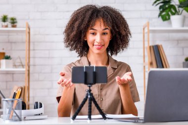 Skype 'ta öğretmenle çevrimiçi çalış. Afrika kökenli Amerikalı kadın oturma odasındaki webcam 'de podcast kaydı yapıyor.