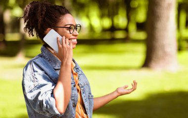 Afrikalı Milenyum Kadını Cep Telefonuyla Konuşuyor, Dışarıda Park 'ta cep telefonu görüşmesi yapıyor. Akıllı Telefondaki Kadın Sohbeti. Modern İletişim Konsepti. Metin için Boş Alan