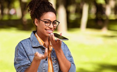 Şehir parkında hoparlörden hoparlörle konuşan mutlu siyahi kadın. Akıllı Telefon Kullanıcı Sohbeti, Modern Mobil İletişim Konsepti. Metin için Boşluk