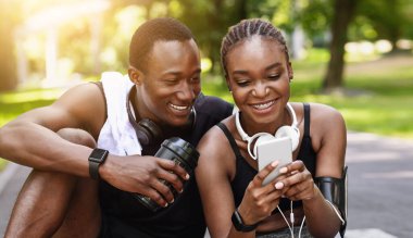 Açık hava eğitiminden sonra akıllı telefon kullanan Siyah Çift Fitness Mobil Uygulamasında Fiziksel Faaliyet Ölçümlerini kontrol ediyor. Yakın çekim.