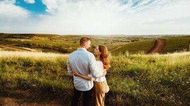 Değer veren bir ilişki. Tarlada birbirine aşık, kucaklaşan ve birbirine bakan kadın ve erkeğin arka plan görüntüsü.