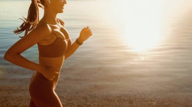 Müzikli Spor. Deniz kenarında koşan güzel bir kız podcast dinliyor, boş yer var.