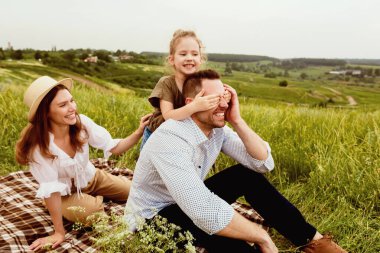 Aile Zamanı Konsepti. Sevimli bebek babasının gözlerini arkadan kapatıyor, çayırda oynuyor.