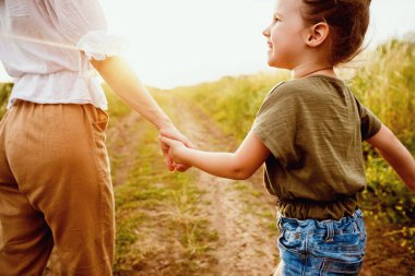 Hayata Dönüş Konsepti. Anne küçük kızını elinden tutuyor, birlikte yürüyor.