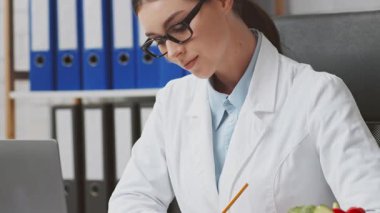 Çalışkan bir dietisyen, çağdaş bir klinikteki hasta dosyalarını inceliyor. Avrupa 'daki uygulamasında sağlık ve refahı destekleyecek beslenme stratejileri geliştirmeye odaklanmış durumda..