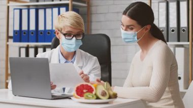 Bir sağlık uzmanı, klinikte bir müşteriyle beslenme konusunu tartışır. Diyetisyen, beslenme bilgileri ve yemek seçenekleri sunarak, modern ortamlarda sağlıklı yaşam biçimleri sunuyor..