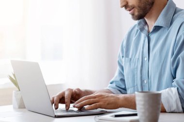 İçişleri Bakanlığı 'nda dizüstü bilgisayarda çalışan yakışıklı serbest çalışan, e-postaları cevaplayan, bilgisayar klavyesinde yazan, müşterilerle iletişim kuran, uzaktan çalışmayı seven, kopyalama alanı ile yan görünümü olan erkek.