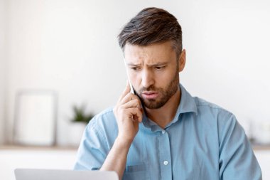 Erkek girişimcinin iş yerinde dizüstü bilgisayarla ilgili sorunları var, cep telefonuyla müşteri desteği ile konuşuyor, ofisteki işyerinde kötü internet bağlantısı olan endişeli adam, boş alan...