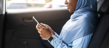 Gülümseyen Müslüman Kadın Girişimci, Smartphone 'a göz gezdirirken, taksiye binerken, ofise giderken, cep telefonuyla mesajlaşırken, e-postalara cevap verirken, boş alanla yan görünümde...