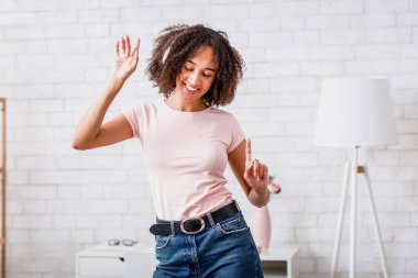 Boş zaman, evde yalnız ve hobi. Kulaklıklı, kulaklıklı, mutlu, Afro-Amerikalı bir kadın. Coronavirus salgını sırasında evdeki en sevdiği müzikle dans ediyor.