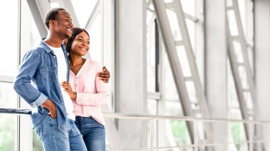 Havaalanında romantik bir çift. Mutlu Siyahi Adam ve Kadın Birlikte Seyahat Ediyor, Genç Afrikalı Amerikalı eşler Terminalde Panoramik Pencereler önünde Ayrılışı Beklerken, Boşluğu Kopyala