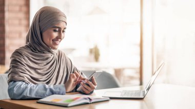 Kafede çalışan, müşterilerle cep telefonunda sohbet eden, boş alan olan Arap kadın.