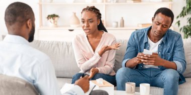 Akıllı telefon bağımlılığı. Sinirli Afrikalı eş, umursamaz eşi telefonuyla meşgulken, ilgisiz kocasının aile danışmanına olan ilgisiz kocasından yakınıyor.