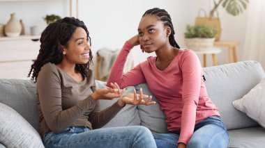Bored black lady listening to her girlfriend with annoyed face expression, fake friendship concept. Two african american women talking, emotional lady looking for support and attention, copy space