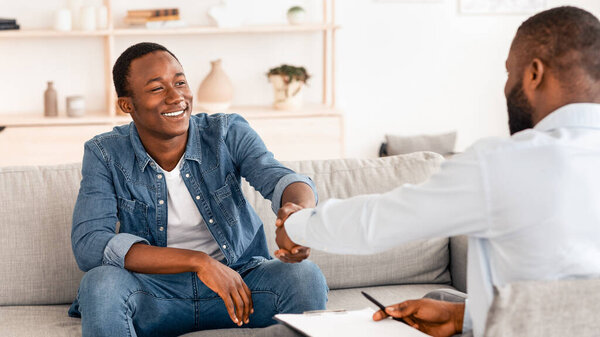 Gratittude For Work. Black Man Handshaking With Psychologist After Therapy Session Meeting, Sitting On Couch At His Office