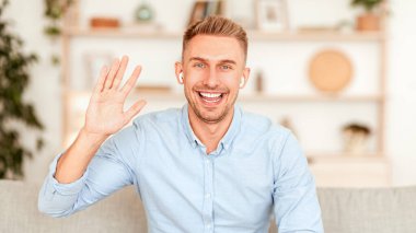 - Selam. Milenyumdan gelen olumlu bir adam, eli kameraya gülümseyen, koltukta oturan ve kulaklık takan bir adam.