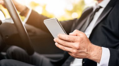 Sürücü güvenliği kavramı. İş adamlarının kullandığı araba, cep telefonu, iş toplantılarının yeri, yan görüş, fotokopi alanı. Araba kullanırken akıllı telefon kullanan tanınmayan bir adam