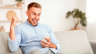 Çevrimiçi zaferi kutlayan aşırı neşeli yakışıklı adam, akıllı telefonu tutan büyük anlaşma ya da iş başarısı, kopyalama alanı