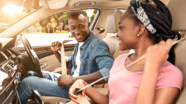 Genç siyah çift arabayla seyahat edecek, emniyet kemerlerini bağlayacaklar.