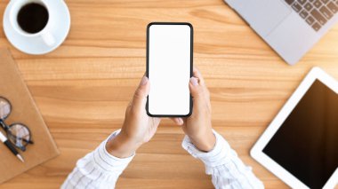 Yöneticinin iş yerindeki ahşap masada oturması, beyaz ekranlı akıllı telefonu tutması, maket, düz alan