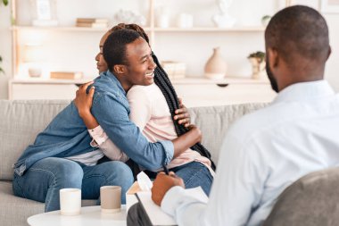 Etkili Çiftler Terapisi. Mutlu Siyahi Eşler Evlilik Danışmanlığı 'nda başarılı bir uzlaşmadan sonra sarılıyor, Afrikalı erkek ve kadını seviyor, kurtarılmış evliliği kutluyor.