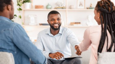 Başarılı terapiden sonra mutlu siyah çiftle el sıkışan aile danışmanı terapistin seçici odak noktası.