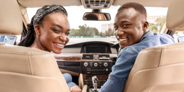 Ön koltuklarda oturan, kameraya gülümseyen, hafta sonu gezisi yapan güzel siyahi bir aile. Yepyeni bir lüks otomobilde poz veren Afro-Amerikan kadın ve erkek.