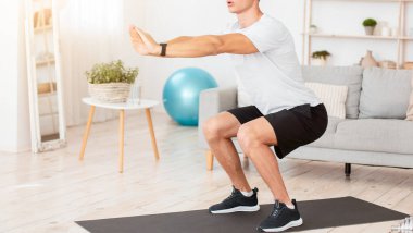 Evde kovid 19 karantinası sırasında formda kalıyor. Spor giyimli genç bir adam ve sabahları oturma odasının iç kısımlarına fitness takip cihazıyla çömeliyor.