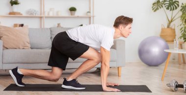 Spor, esneme, evde online egzersiz. Başlangıçta oturma odasında, iç mekanda, boş alanda antrenman yapan adama odaklandım.