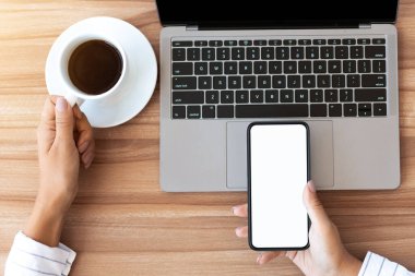 Modern İşyeri. Beyaz ekranlı akıllı telefonu elinde tutan bir kadın ve bir fincan kahve.