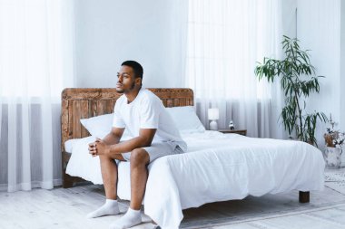 Düşünceli Afrikalı Amerikalı bir adam sabahları yatak odasında yatmayı düşünüyor. Hayat hakkındaki düşünceler, stresli modern hayat kavramı. Metin için Boş Alan