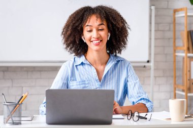 Öğretmen karantina sırasında çevrimiçi çalışıyor. Arkadaş canlısı Afro-Amerikan kadın öğrencilerle çevrimiçi oturma odasında sohbet ediyor.