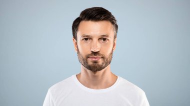 Gri stüdyo arka planında yakışıklı sakallı adamın portresi, boş alan. Erkek dergisi veya blog için poz veren orta yaşlı sakallı adam, gençlik, sağlıklı yaşam tarzı ve erkek kozmetoloji kavramı