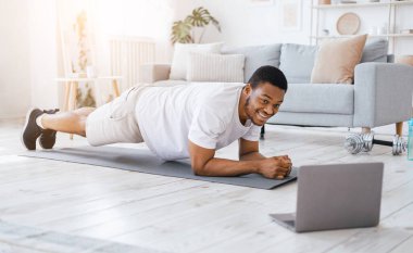 Çevrimiçi antrenman. Evdeki yatak odasında dizüstü bilgisayar eğitimi alan Afrikalı Amerikalı adam.