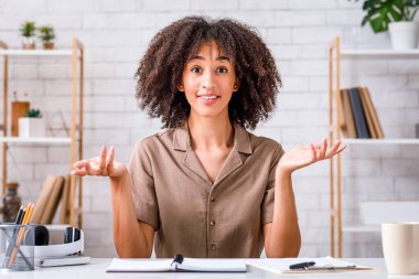 Bilmiyorum ya da belki. Çekici Afro-Amerikan kadın kollarını yana açıyor ve kameraya bakıyor, oturma odasında not defteriyle oturuyor ve video kaydını kaydediyor.