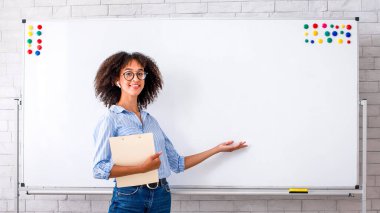 Karantina sırasında giyim, ders ve İngilizce dersi. Gözlüklü ve kablosuz kulaklıklı Afrikalı Amerikalı kadın tablet tutuyor ve evdeki sınıfın içinde dizüstü bilgisayarla kuralları açıklıyor.