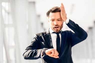 Endişeli iş adamı saatine bakıyor ve kafasına dokunuyor, havaalanı terminalinden geçiyor, boş bir alan. Pahalı takım elbiseli orta yaşlı girişimci gecikti, uçağını kaçırdı. İş seyahati sorunları