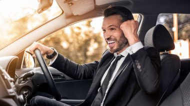 Orta yaşlı işadamı lüks arabasını, yan bakışını, kopyalama alanını sürerken başarısını kutluyor. Başarılı iş toplantısından dönen, yumruğunu sıkan ve çığlık atan mutlu girişimci.