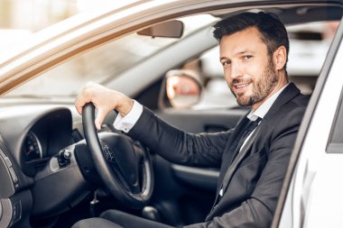 Pahalı bir arabada oturan genç ve mutlu bir girişimci ofise gidiyor.