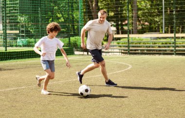 Aktif Yaşam Tarzı Konsepti. Sportif baba oğluyla stadyumdaki yeşil çimlerde futbol oynuyor.