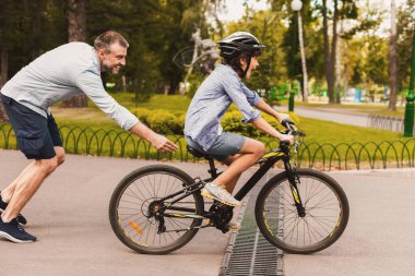 Aile zamanı. Baba oğluna bisiklet sürmeyi öğretiyor. Hafta sonları birlikte vakit geçiriyor.