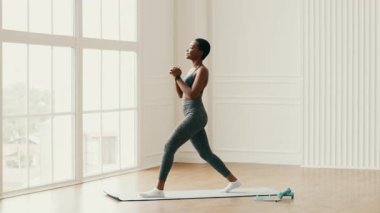 Bir kadın kapalı alanda egzersiz yapar, atletizmini ve kendini spora adadığını gösterir. Parlak, ferah bir ortamda, sağlıklı bir yaşam tarzını yansıtan kararlı bir hamleyi gerçekleştirir..